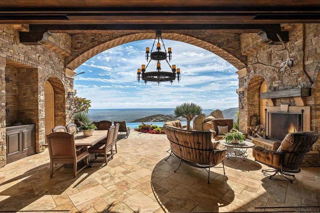 8619 Via Rancho Cielo – Covered Lounge Terrace 8619 Via Rancho Cielo, Rancho Santa Fe: a deep stone arch shelters the outdoor lounge facing the distant horizon.