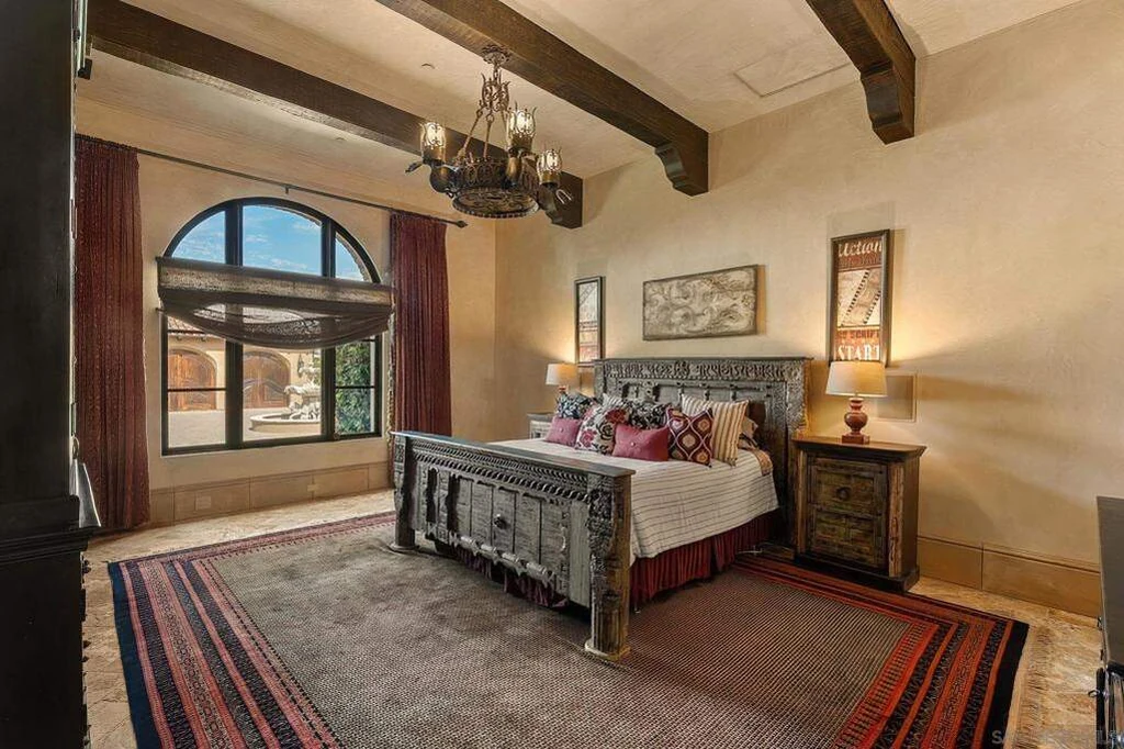 8619 Via Rancho Cielo – Guest Bedroom 8619 Via Rancho Cielo, Rancho Santa Fe: a guest bedroom continues the home’s beams, arches and warm finishes.